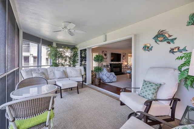 sunroom / solarium featuring ceiling fan and a fireplace