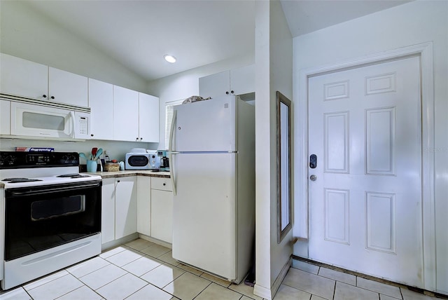 kitchen featuring light tile patterned floors, white cabinets, vaulted ceiling, and white appliances