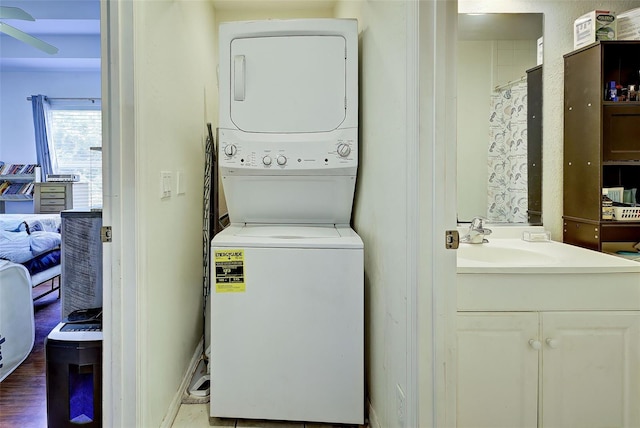 washroom with sink, wood-type flooring, and stacked washer / drying machine