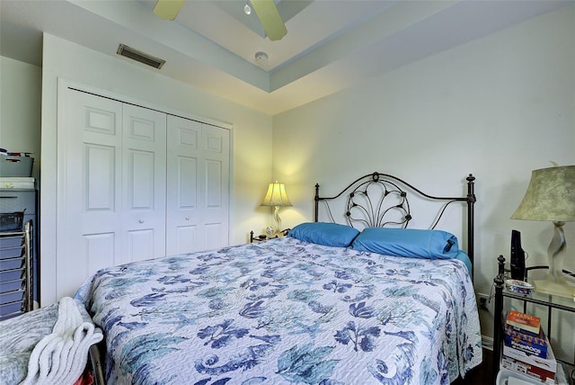 bedroom featuring a tray ceiling, a closet, and ceiling fan