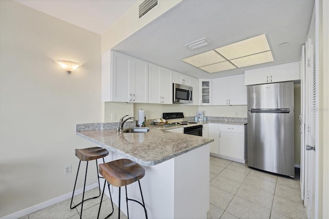 7070 Placida Rd Unit 1221, Placida, FL 33946 - kitchen with stainless steel appliances, a sink, a peninsula, light stone counters, and white cabinetry