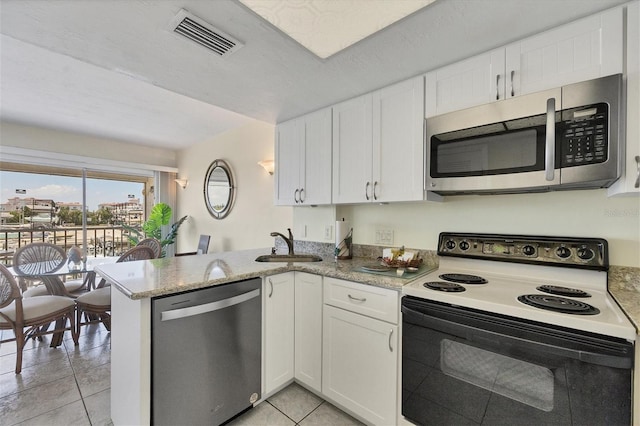 7070 Placida Rd Unit 1221, Placida, FL 33946 - kitchen with stainless steel appliances, white cabinetry, a peninsula, and light tile patterned floors