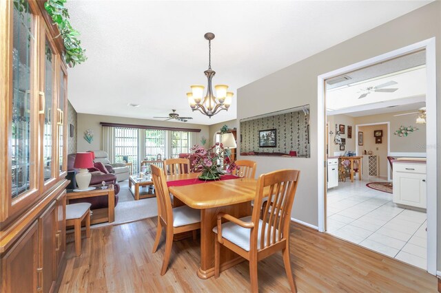 dining area featuring ceiling fan with notable chandelier and light hardwood / wood-style floors