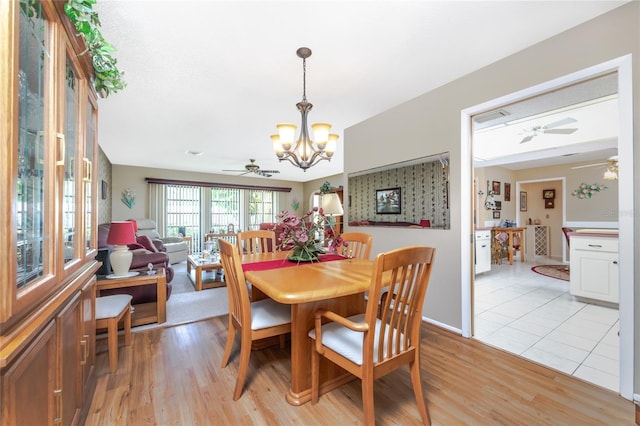 dining space with light wood-style floors and ceiling fan with notable chandelier