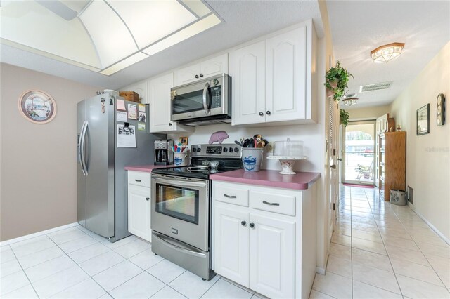 kitchen with appliances with stainless steel finishes, light tile patterned floors, and white cabinets