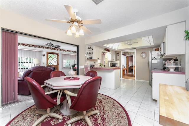 dining area with light tile patterned floors, a textured ceiling, and a ceiling fan