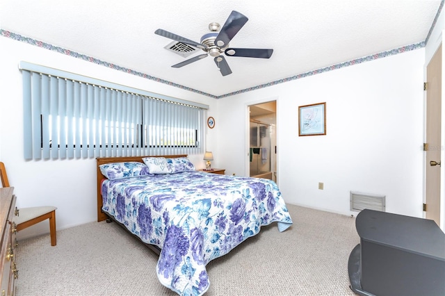 carpeted bedroom featuring a textured ceiling, ensuite bath, and ceiling fan