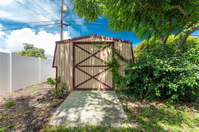 view of gate with an outbuilding, fence, and a storage shed