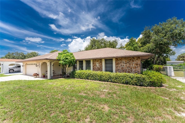 single story home with driveway, stone siding, an attached garage, fence, and a front lawn