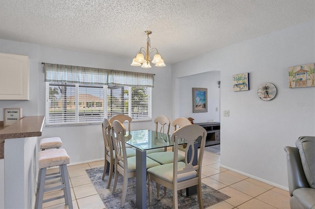 dining area featuring light tile patterned flooring, a chandelier, and a textured ceiling