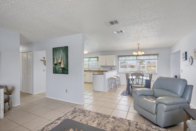 living room featuring light tile patterned flooring, plenty of natural light, a notable chandelier, and a textured ceiling