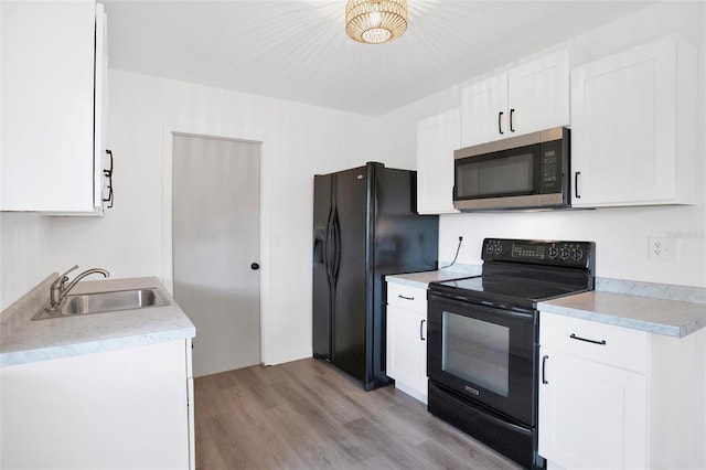 kitchen featuring white cabinetry, sink, light hardwood / wood-style flooring, and black appliances