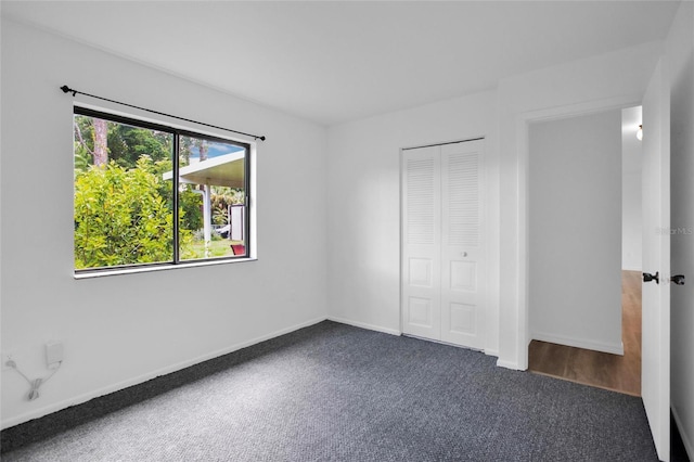 unfurnished bedroom with a closet and dark colored carpet