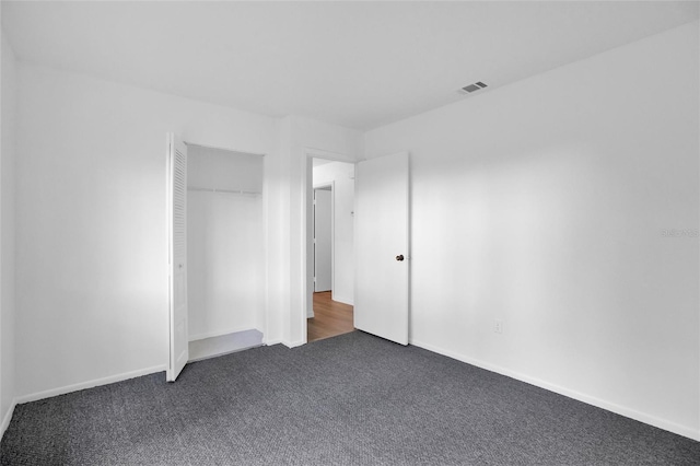 unfurnished bedroom with dark carpet and a closet