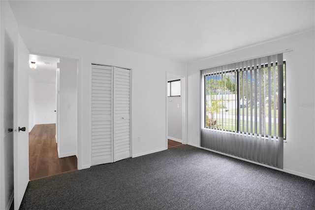 unfurnished bedroom with a closet and dark colored carpet