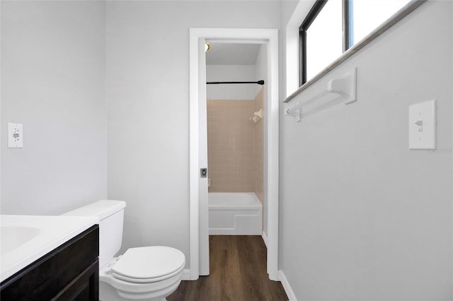 full bathroom with hardwood / wood-style flooring, tiled shower / bath, vanity, and toilet