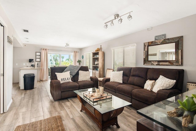 living room featuring rail lighting and light hardwood / wood-style flooring