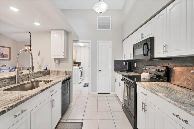 kitchen with light tile patterned floors, white cabinets, black appliances, hanging light fixtures, and sink