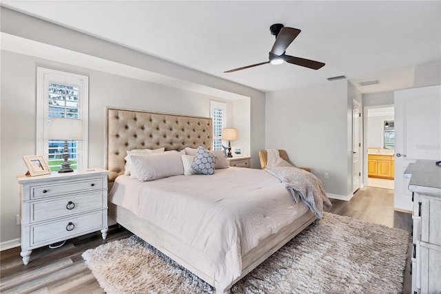 bedroom featuring dark hardwood / wood-style flooring, ceiling fan, and ensuite bathroom