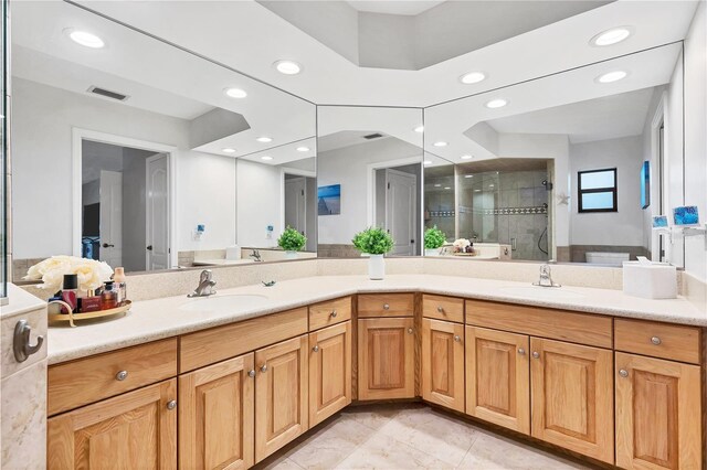 bathroom featuring tiled shower, tile patterned floors, and double sink vanity