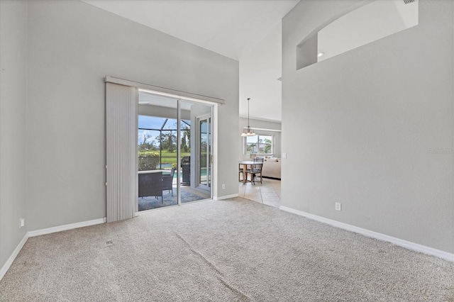 empty room with a sunroom, light colored carpet, a towering ceiling, and baseboards