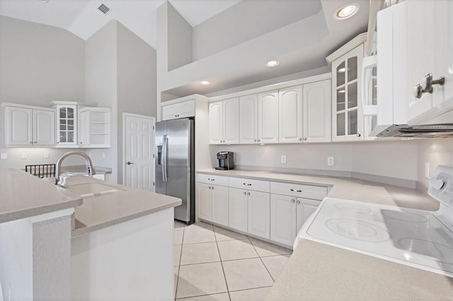 kitchen with white range oven, stainless steel fridge with ice dispenser, and white cabinets