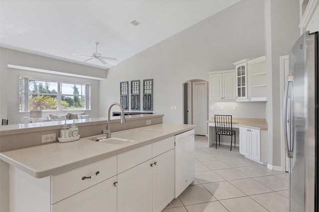 kitchen featuring glass insert cabinets, light countertops, arched walkways, and freestanding refrigerator