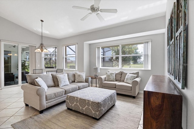 living room with ceiling fan with notable chandelier, vaulted ceiling, plenty of natural light, and light tile patterned floors