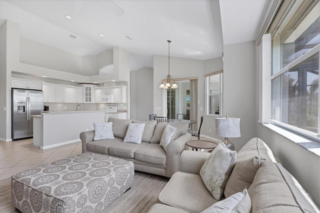 living area with baseboards, lofted ceiling, light tile patterned flooring, a notable chandelier, and recessed lighting