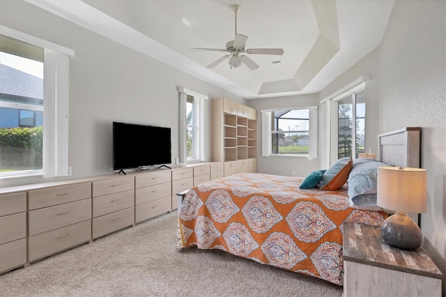 bedroom featuring ceiling fan, light colored carpet, and a raised ceiling