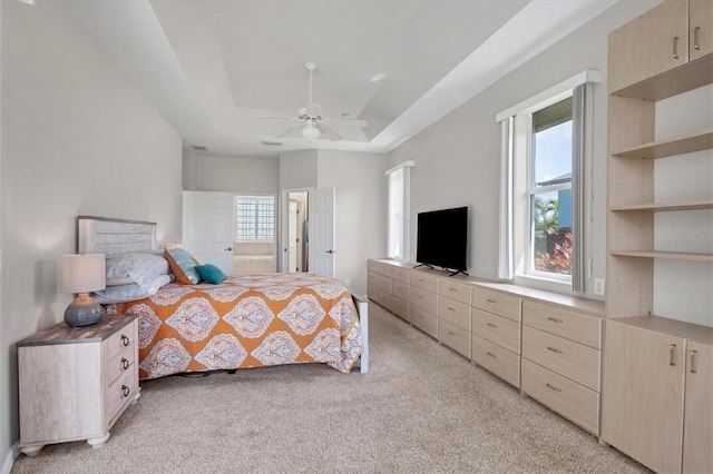 bedroom featuring visible vents, connected bathroom, light colored carpet, ceiling fan, and a tray ceiling