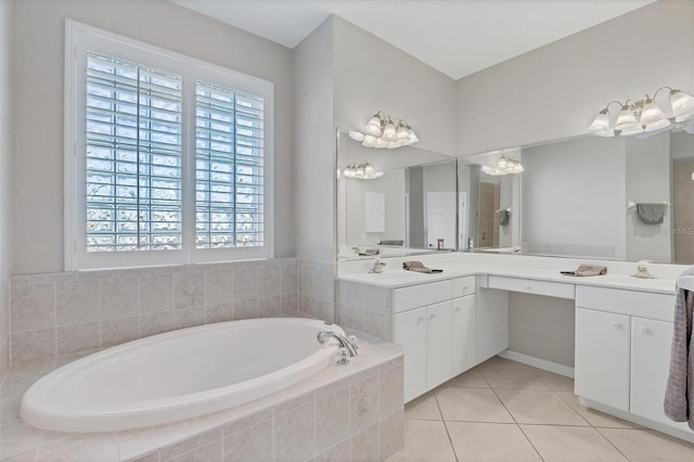 bathroom with tile patterned flooring, tiled tub, and vanity