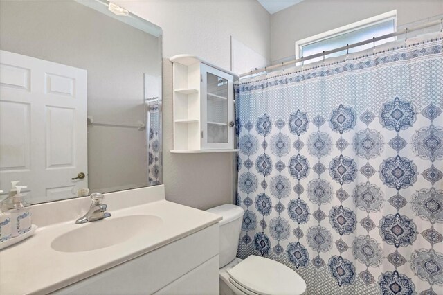 bathroom featuring curtained shower, vanity, and toilet