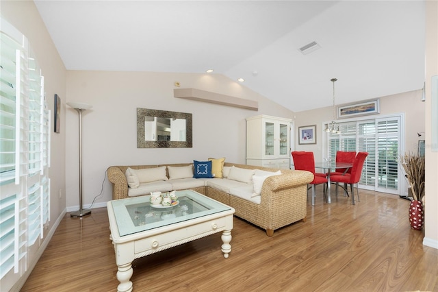 living room with a chandelier, light hardwood / wood-style flooring, and vaulted ceiling