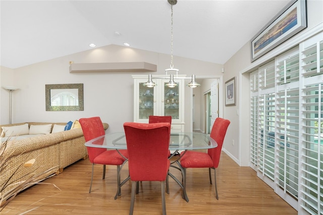 dining room with vaulted ceiling and light hardwood / wood-style floors