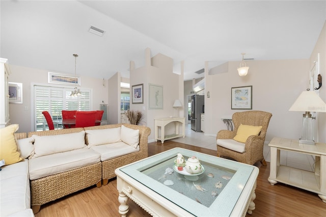 living room with lofted ceiling, light hardwood / wood-style floors, and a notable chandelier