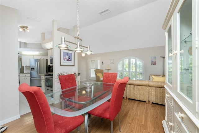 dining space with light hardwood / wood-style flooring and vaulted ceiling