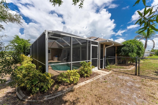 rear view of house featuring a lanai and a fenced in pool