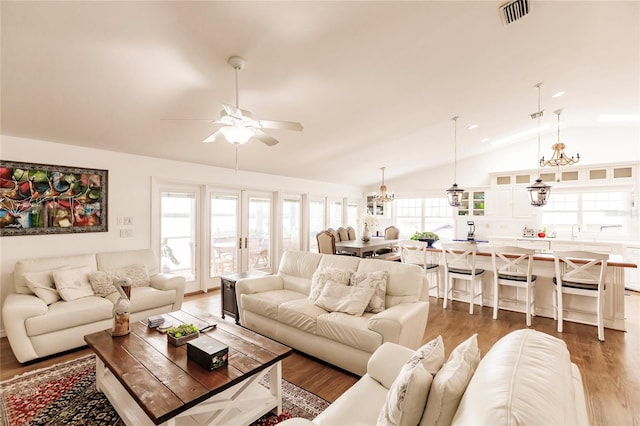 living room with lofted ceiling, french doors, ceiling fan with notable chandelier, dark wood-type flooring, and sink