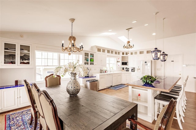 dining area featuring an inviting chandelier, sink, light wood-type flooring, and lofted ceiling