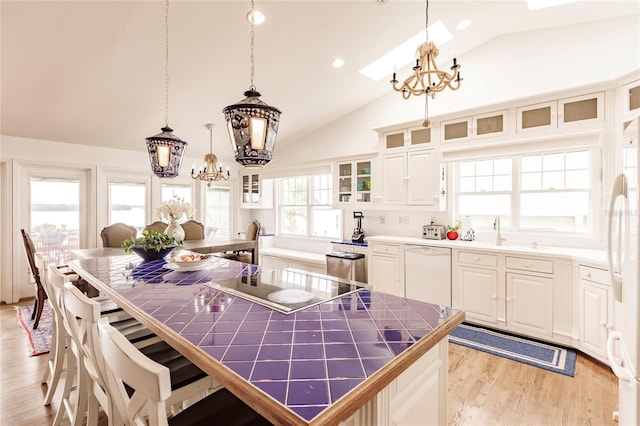 kitchen with decorative light fixtures, light hardwood / wood-style flooring, an inviting chandelier, and white appliances