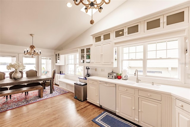 kitchen featuring light hardwood / wood-style flooring, an inviting chandelier, white dishwasher, decorative light fixtures, and sink