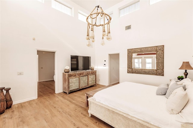 bedroom with hardwood / wood-style flooring, a towering ceiling, and a notable chandelier