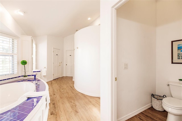 bathroom featuring a bathing tub, hardwood / wood-style flooring, and toilet