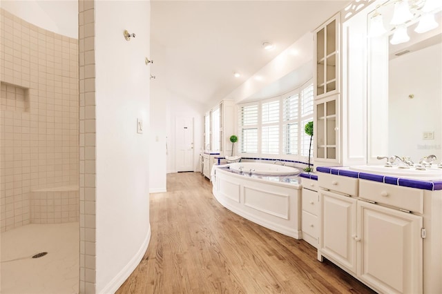 interior space featuring light hardwood / wood-style floors, sink, lofted ceiling, and tile counters