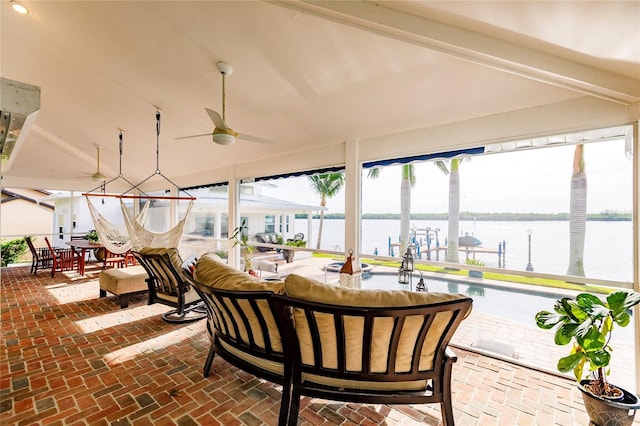 sunroom featuring a water view and ceiling fan