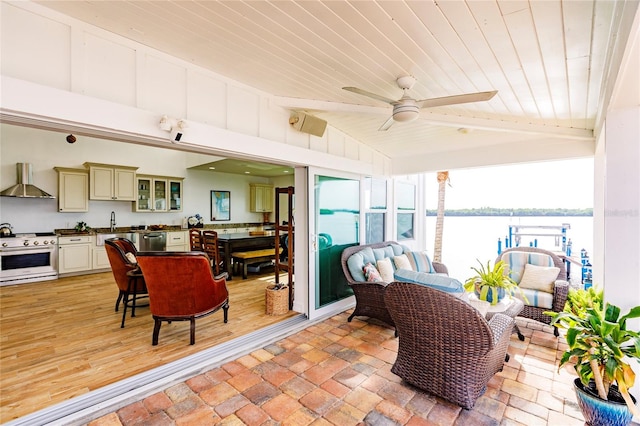 sunroom featuring sink, a water view, wooden ceiling, and ceiling fan