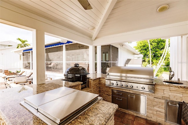 view of patio featuring grilling area, exterior kitchen, and a sunroom