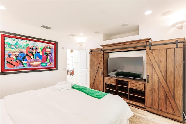 bedroom featuring wood-type flooring and a barn door