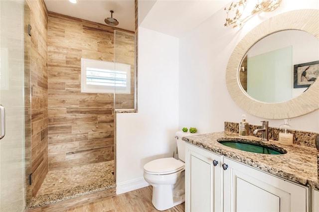 bathroom featuring tiled shower, vanity, wood-type flooring, and toilet